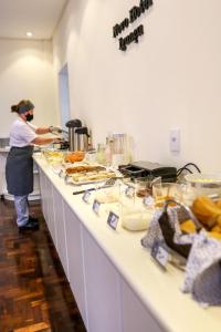 a woman in a kitchen preparing food on a counter at Novo Hotel Iguaçu in Pôrto União