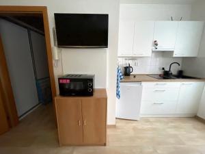 une cuisine avec des placards blancs et une télévision sur un comptoir dans l'établissement Studio Paula, à Rokytnice nad Jizerou