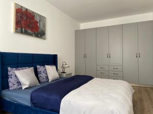 um quarto com uma cama azul e armários brancos em Napoca Apartament em Floreşti