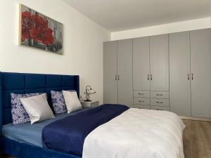 a bedroom with a blue bed and white cabinets at Napoca Apartament in Floreşti