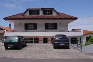 two cars parked in a parking lot in front of a house at Scenic Comfort D in Ponta Delgada