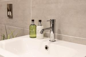 a bathroom sink with two soap bottles on it at Clearwater - Luxury lakeside house in Borwick