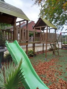 un tobogán verde en un parque infantil con cenador de madera en B&B Aalsters genot en Aalst