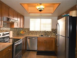 a kitchen with wooden cabinets and a stainless steel refrigerator at MESQUITE ZEN RETREAT in Palm Springs