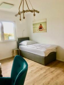 a bedroom with a bed and a blue chair at Hostel Hof Kranichstein in Kluis