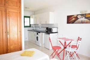 a kitchen with red chairs and a table and a microwave at Caleta Paraiso Sea View 137 in Costa de Antigua