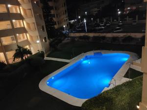 a blue swimming pool in the middle of a building at night at BEACH FOREST PARADISE in Cabopino