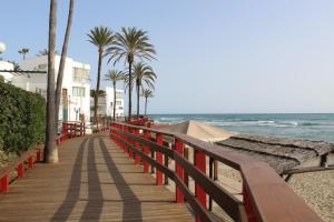 a wooden boardwalk leading to the beach with palm trees at BEACH FOREST PARADISE in Cabopino