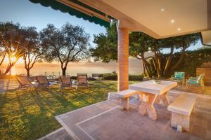a patio with a table and chairs and the ocean at Villetta Blue Panorama With Jacuzzi in Torri del Benaco
