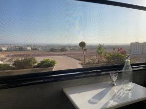 eine Glasflasche auf einem Tisch vor einem Fenster in der Unterkunft Scenic Family Apt overlooking Agadir in Agadir