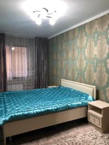1 dormitorio con 1 cama con edredón azul en квартира с красивым видом на море, en Aktau