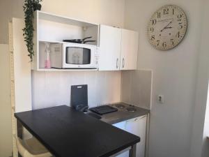 een keuken met een magnetron en een klok aan de muur bij Le Cosy Studio Logement entier [Parking Gratuit] in Algrange