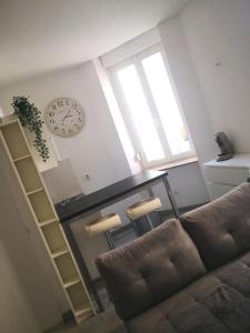 een woonkamer met een bank en een klok aan de muur bij Le Cosy Studio Logement entier [Parking Gratuit] in Algrange