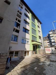 une personne debout devant un grand bâtiment dans l'établissement Apartment M, à Višegrad