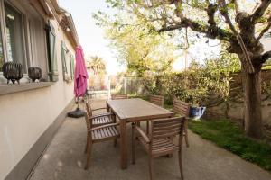 una mesa de madera y sillas en un patio en Maison Manon, Piscine - Clim - Jardin, en Arles