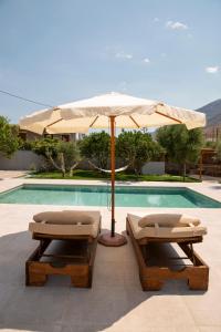 two lounge chairs and an umbrella next to a pool at Mani Luxury Villa with Private Pool in Khalíkia