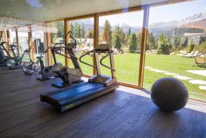 a gym with cardio equipment in a room with a large window at Hotel Gran Paradiso in San Cassiano