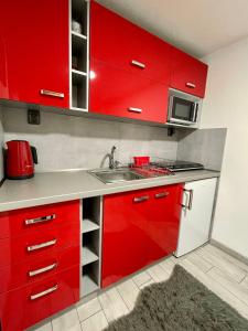a red kitchen with a sink and red cabinets at Apartmán Klaudia in Ružomberok