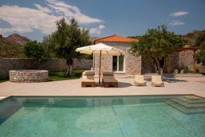 a swimming pool with an umbrella and chairs and a house at Mani Luxury Villa with Private Pool in Khalíkia