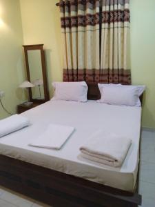 Un dormitorio con una cama con toallas blancas. en Suwani Pinnawala Homestay en Pinnawala