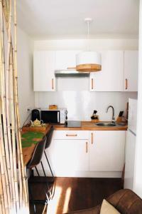 uma pequena cozinha com armários brancos e uma mesa em studio ZEN gare part Dieu em Lyon