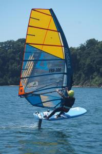 a man on a surfboard with a sail on the water at La maison d'hôtes Ty Pic in La Vicomté-sur-Rance