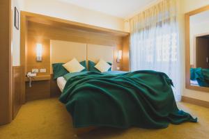 una camera da letto con un grande letto con lenzuola verdi di B&B Garni Villa Campitello a Campitello di Fassa