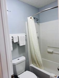 y baño con aseo blanco y ducha. en Coachway Inn, en Luling