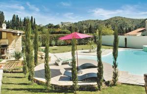 ブルボンにあるBeautiful Home In Boulbon With 3 Bedrooms, Wifi And Swimming Poolのピンクの傘と木々が植わるスイミングプール