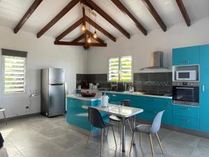 a kitchen with blue cabinets and a table with chairs at LES VILLAS PAMEYAQUE 2 F2 avec 1 piscine, 1 F3 avec 1 piscine privée, Superbe Vue Mer in Rivière-Salée