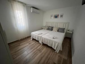 1 dormitorio con cama blanca y suelo de madera en La Vida es Bella Córdoba, en Córdoba