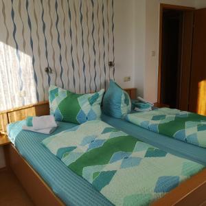 a bed with a green and blue comforter and pillows at Traumblick Am Bartelsborn in Kleinern