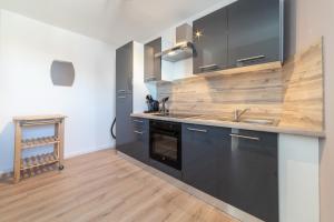 eine Küche mit schwarzen Schränken und einer hölzernen Arbeitsplatte in der Unterkunft ✮✮✮ Les Suites GOLD et AMAZONIE ✮✮✮ in Mulhouse