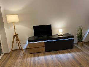 a living room with a tv on a dresser with a lamp at Ferienwohnung Auersbergblick in Schönheide