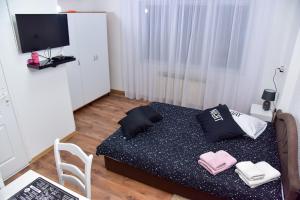 um pequeno quarto com uma cama e uma televisão em Apartmani Koko em Banja Luka