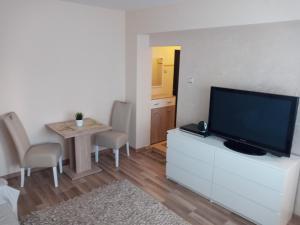 ein Wohnzimmer mit einem TV und einem Tisch mit Stühlen in der Unterkunft Apartman Nera in Zenica