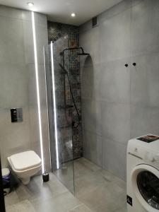 a bathroom with a shower and a toilet and a washing machine at Apartament w Centrum in Szczecin +11 photos