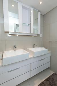 two sinks in a white bathroom with mirrors at Abeach Apartment on 3rd in Gaborone