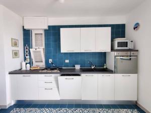 サン・フォカにあるVillino sul mareの青いタイル張りの壁、白いキャビネット付きのキッチンが備わります。