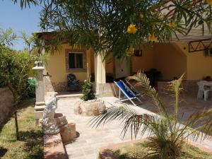a house with a patio with a blue lawn chair at Villa Primofiore di Vendicari in La Banca