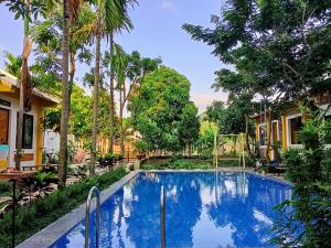 a swimming pool in front of a house with trees at Mai Home Ninh Bình in Ninh Binh