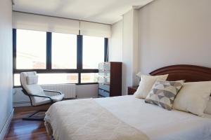um quarto com uma cama, uma cadeira e janelas em APARTAMENTO PORTUTXU em Mundaka