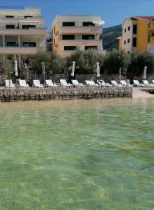 a beach with chairs and umbrellas and the water at Olea in Tivat