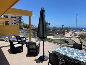 een patio met een tafel en stoelen en een parasol bij RentOnTheBeach in Los Cristianos
