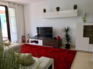 uma sala de estar com uma televisão e um tapete vermelho em Penthouse Los Arqueros golf em Benahavís
