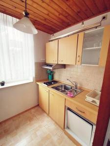 uma cozinha com armários de madeira, um lavatório e uma janela em Villa Rapunzel em Rathen