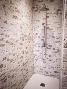 y baño con ducha y pared de piedra. en L'Essentiel, en Gujan-Mestras