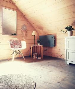 a room with a bed and a chair and a television at Domki Między Drzewami in Bartoszylas