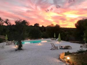 a swimming pool with a sunset in the background at Trulli Pietraverde in Ceglie Messapica