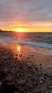 una puesta de sol en una playa con el océano en Ferienwohnung Daliah, en Wangels